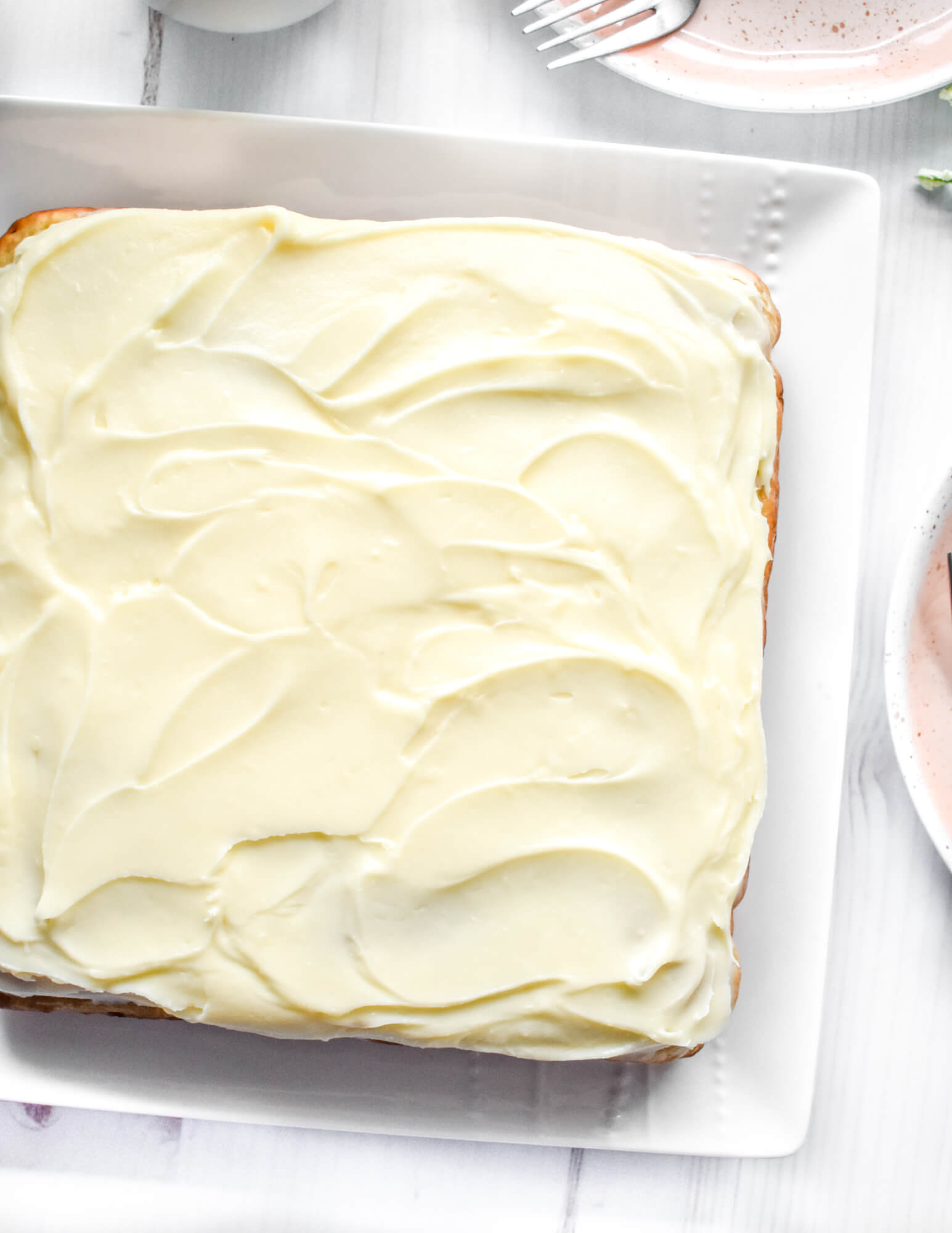 Closeup of a square shaped banana cake with cream cheese frosting.