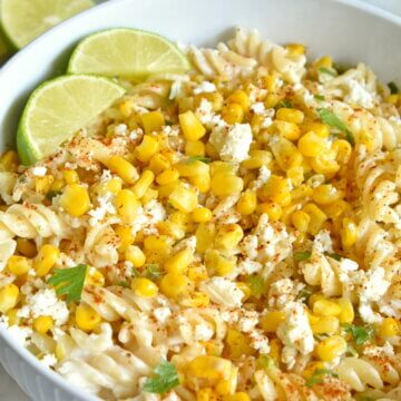A bowl of Healthy Mexican Street Corn Pasta Salad topped with lime wedges.