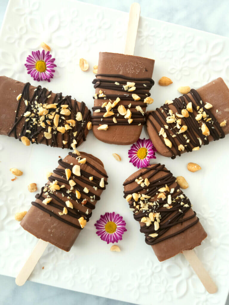 Vegan Chocolate Peanut Butter Fudgsicles on a platter with little flowers.
