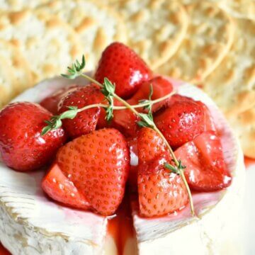 baked brie with balsamic roasted strawberries appetizer on a platter with crackers