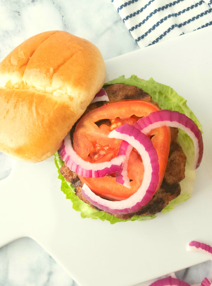 Close up of a Classic Homemade Hamburgers topped with fresh tomato, onions and lettuce.
