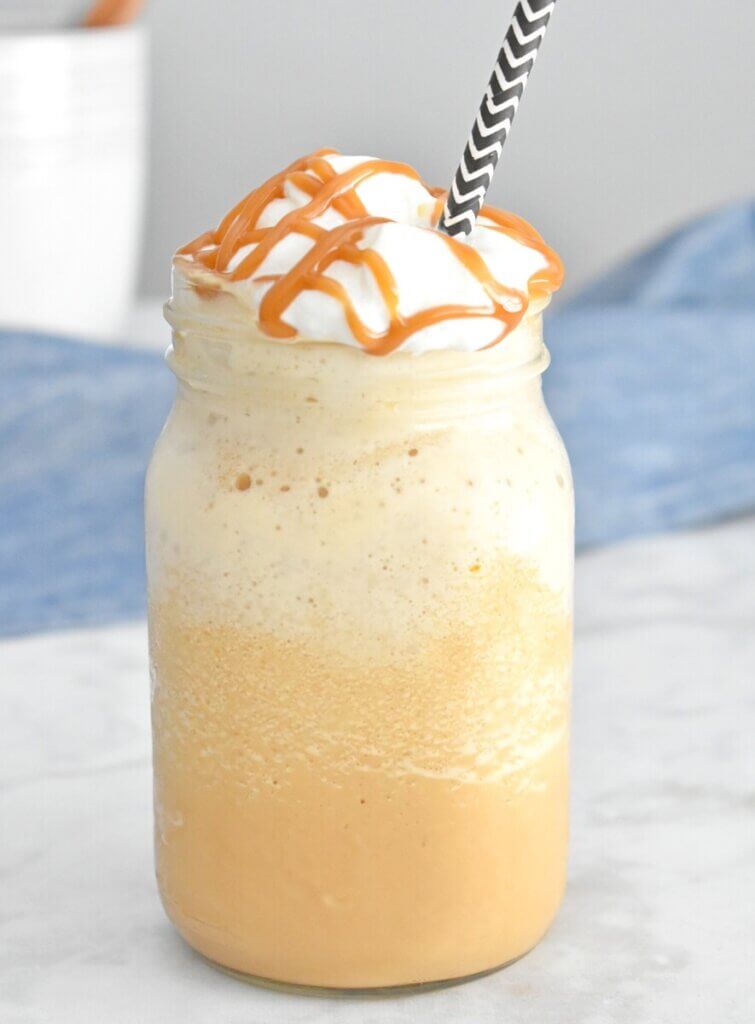 Caramel frappuccino starbucks copycat in a mason jar with whip cream and caramel drizzle.