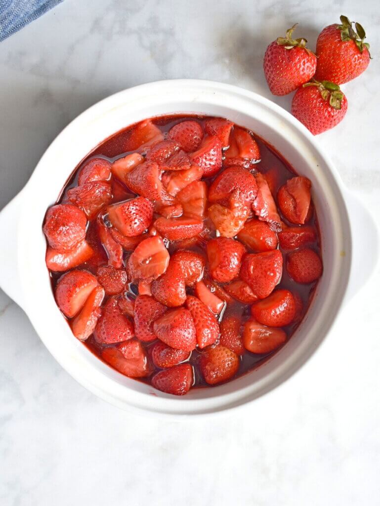 Baking dish of Balsamic Roasted Strawberries next to fresh strawberries.
