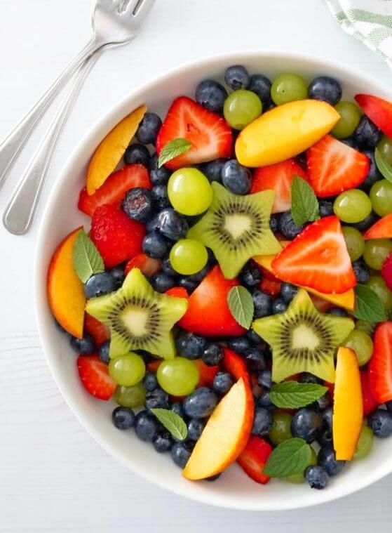 Close up of a bowl of Summer Fruit Salad with berries, grapes, peaches and Fresh Mint