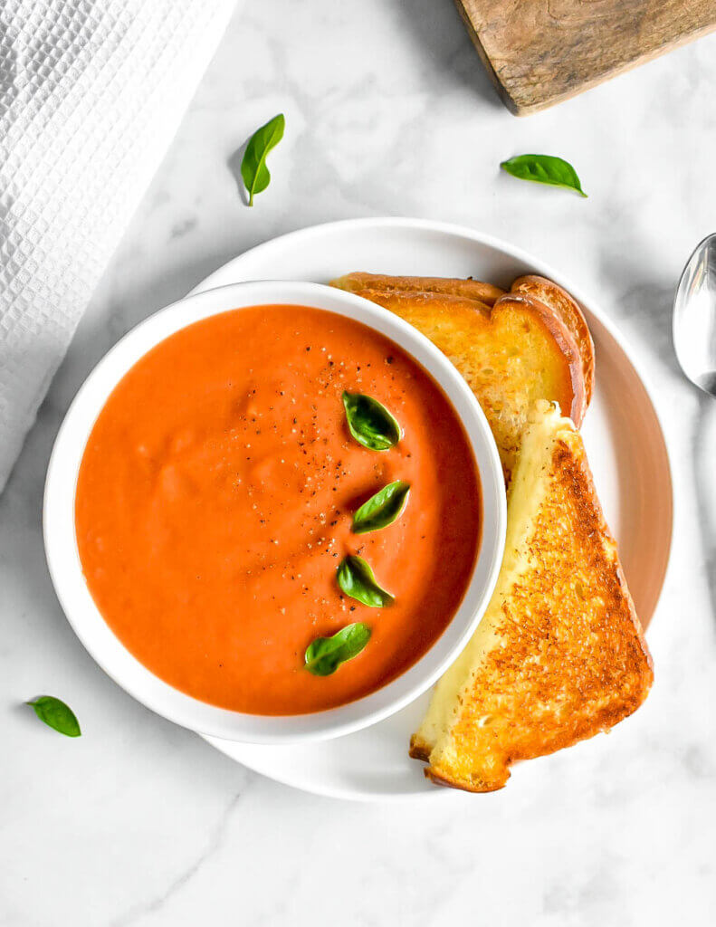 Topview of a bowl of Creamy Tomato Soup served with a grilled cheese sandwich.