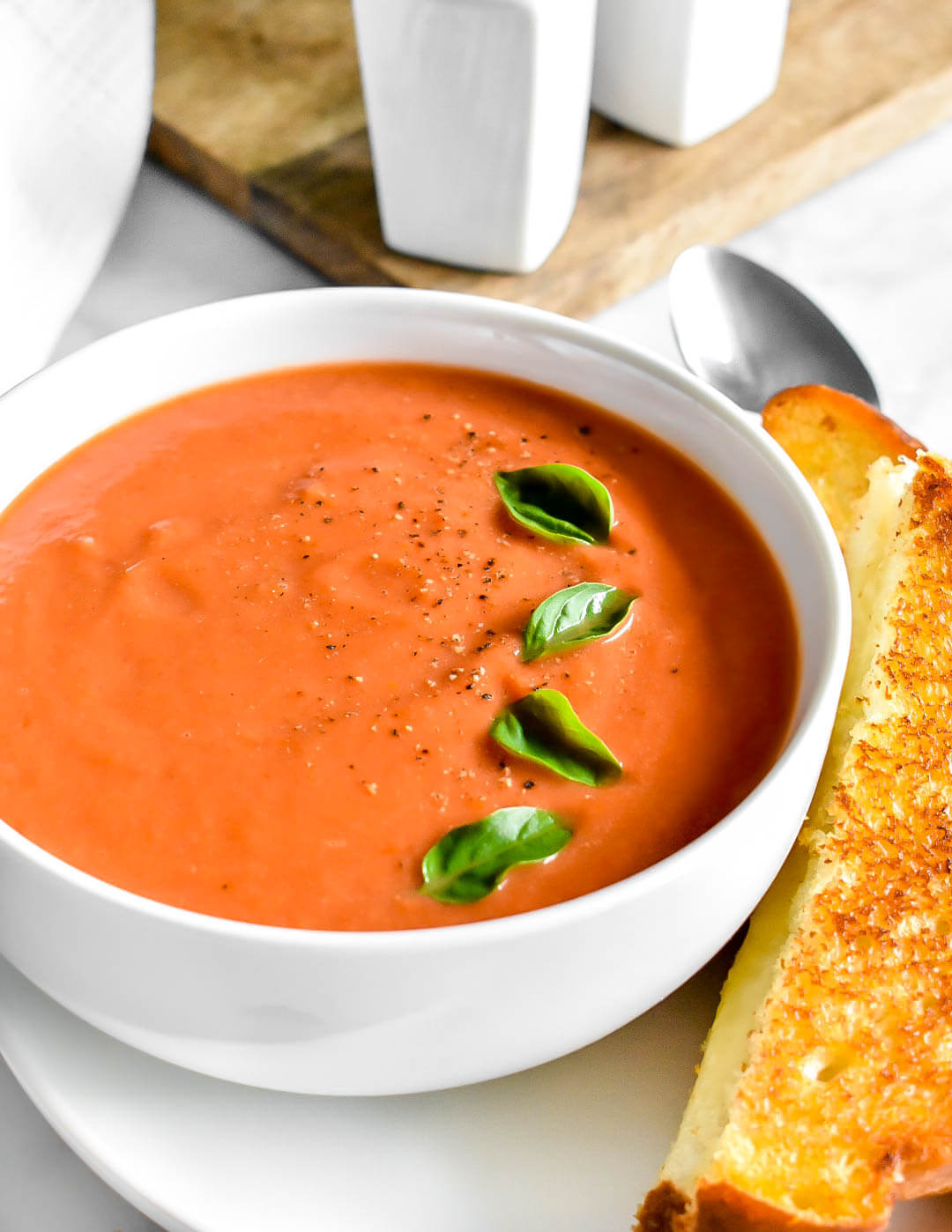 A bowl of tomato soup with fresh basil leaves on top.
