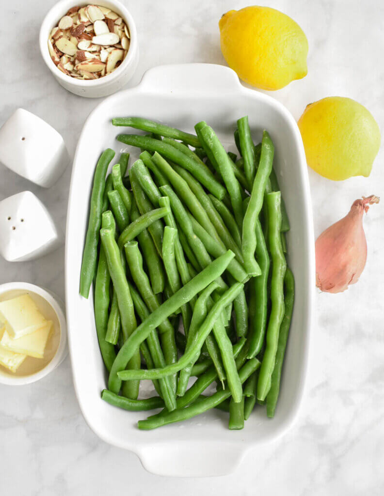 The ingredients in Green Beans Almondine on a grey marble countertop.