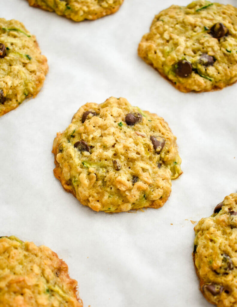 Closeup of a zucchini cookie with oatmeal and chocolate chips on parchment paper.