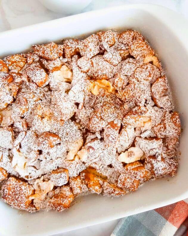 A pan of Pumpkin French Toast Casserole sprinkled with icing sugar.