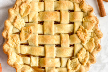 A classic apple pie with a golden brown lattice crust and leaf cut-out crusts designs.
