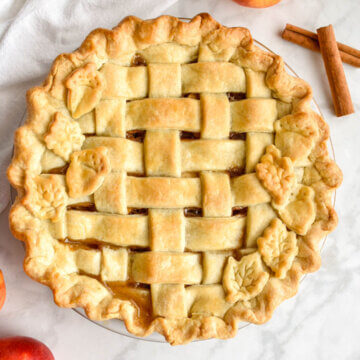 A classic apple pie with a golden brown lattice crust and leaf cut-out crusts designs.