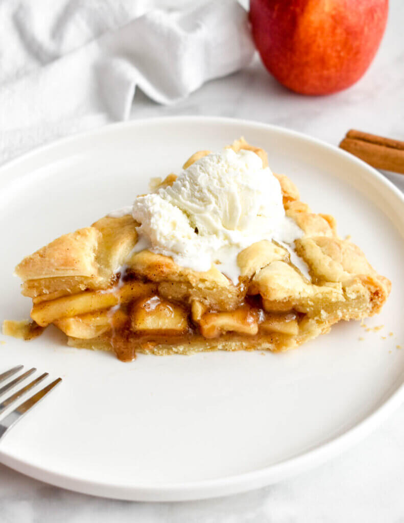 A slice of apple pie with a scoop of vanilla icing.