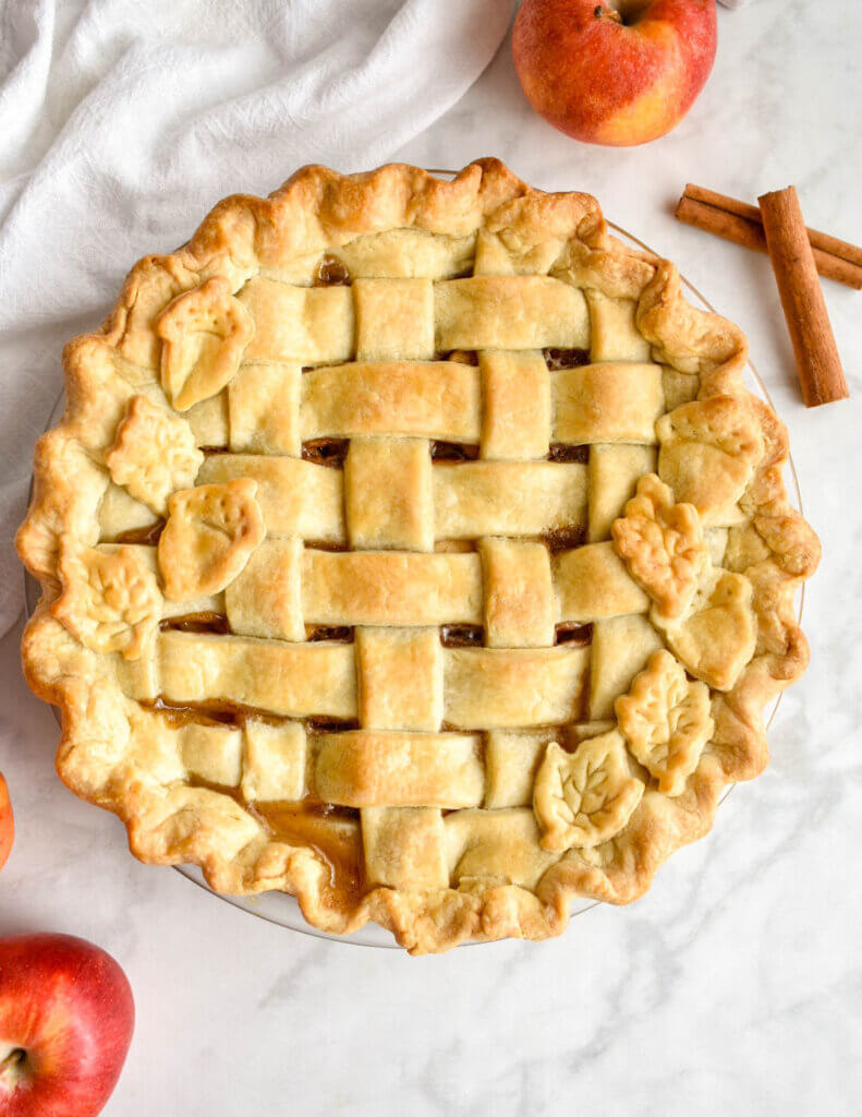 A classic apple pie with a golden brown lattice crust and leaf cut-out crusts designs.