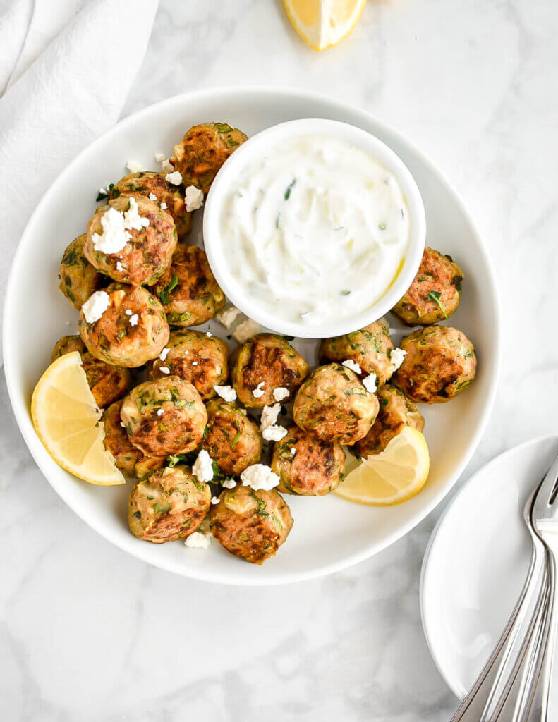 A platter of Greek chicken meatballs made with spinach and feta served with tzatziki dip.