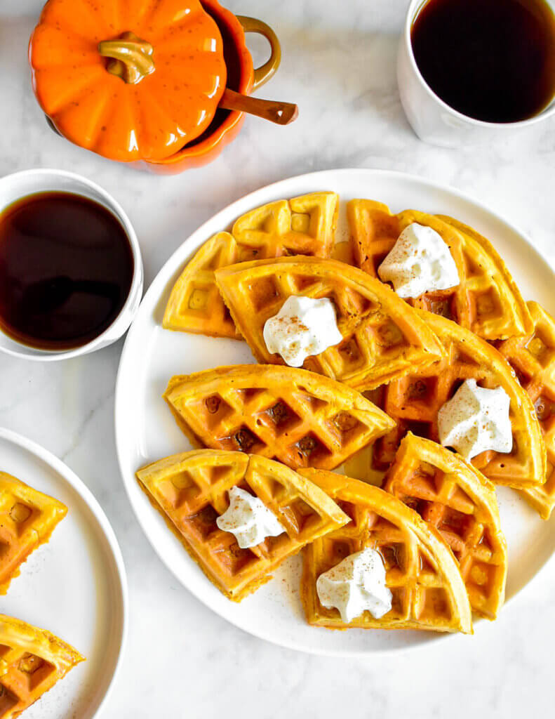 Platter of Pumpkin Spice Waffles topped with a dollop of whip cream.