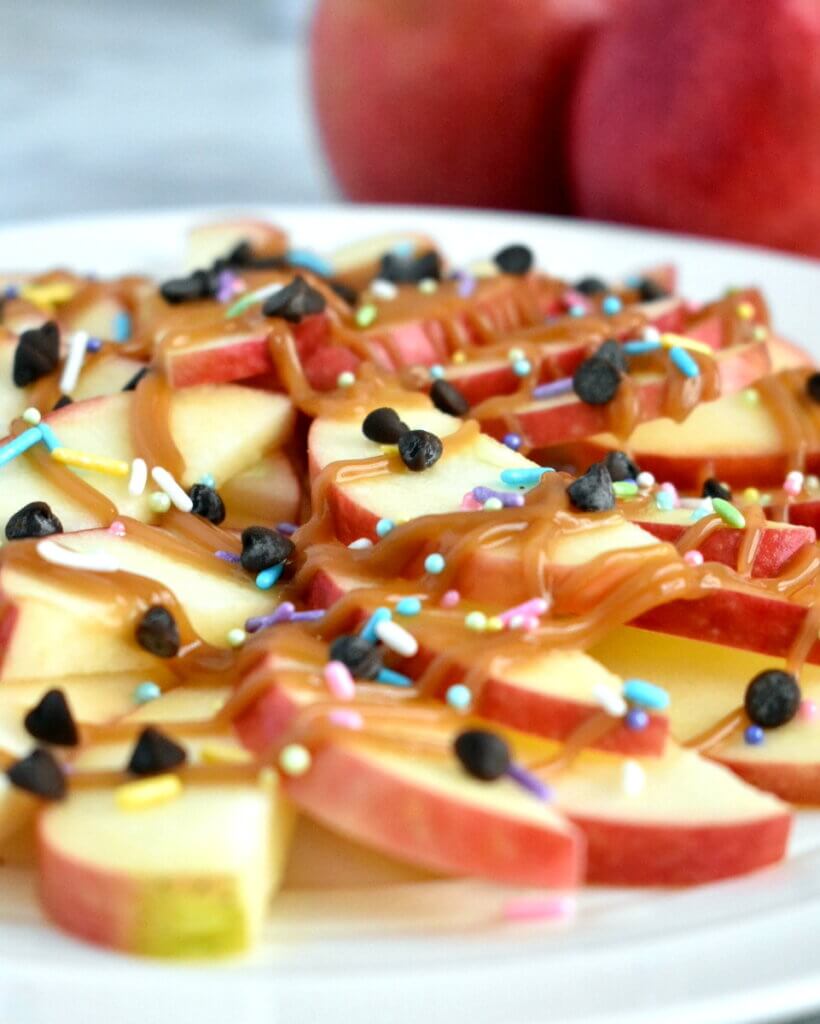 Closeup of apple nacho platter topped with caramel, chocolate chips and sprinkles.