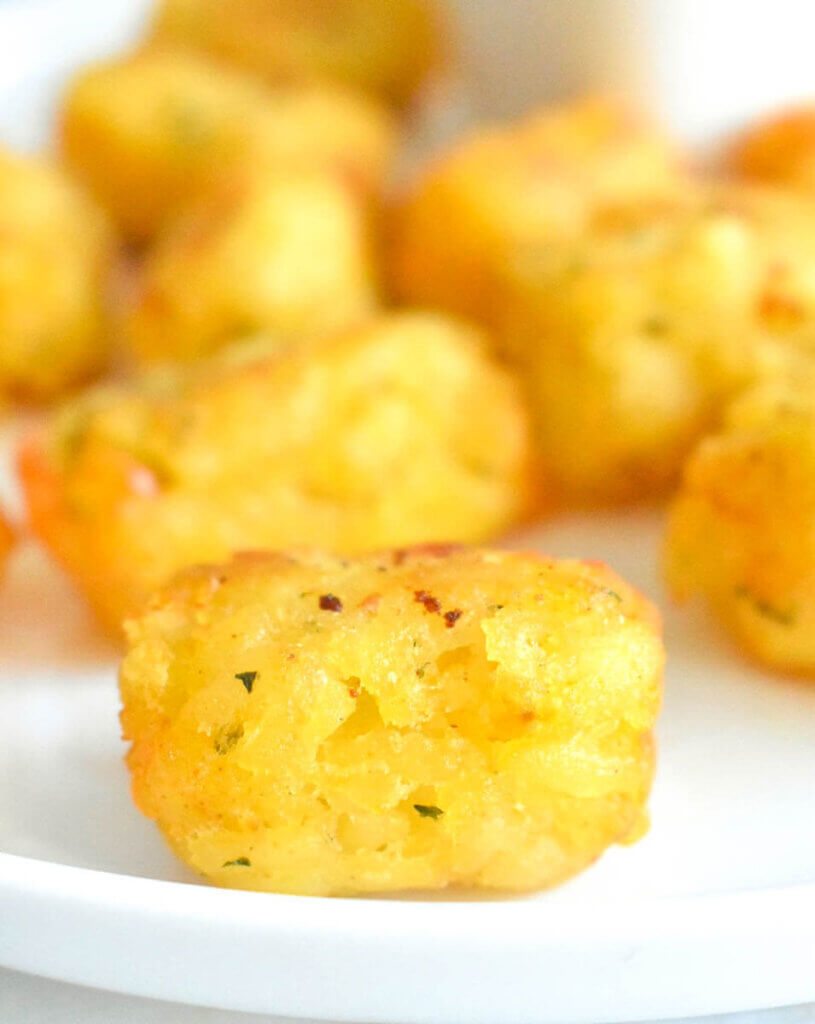 Close up of tater tots on a white plate.