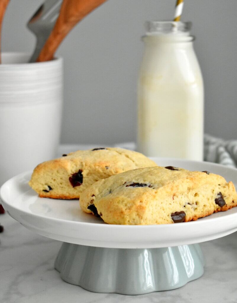 Closeups of Cranberry and Dark Chocolate Scones on a cake stand with a bottle of milk.