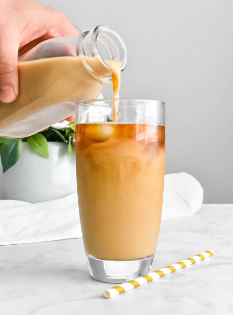 Pumpkin cream being poured into cold brew coffee