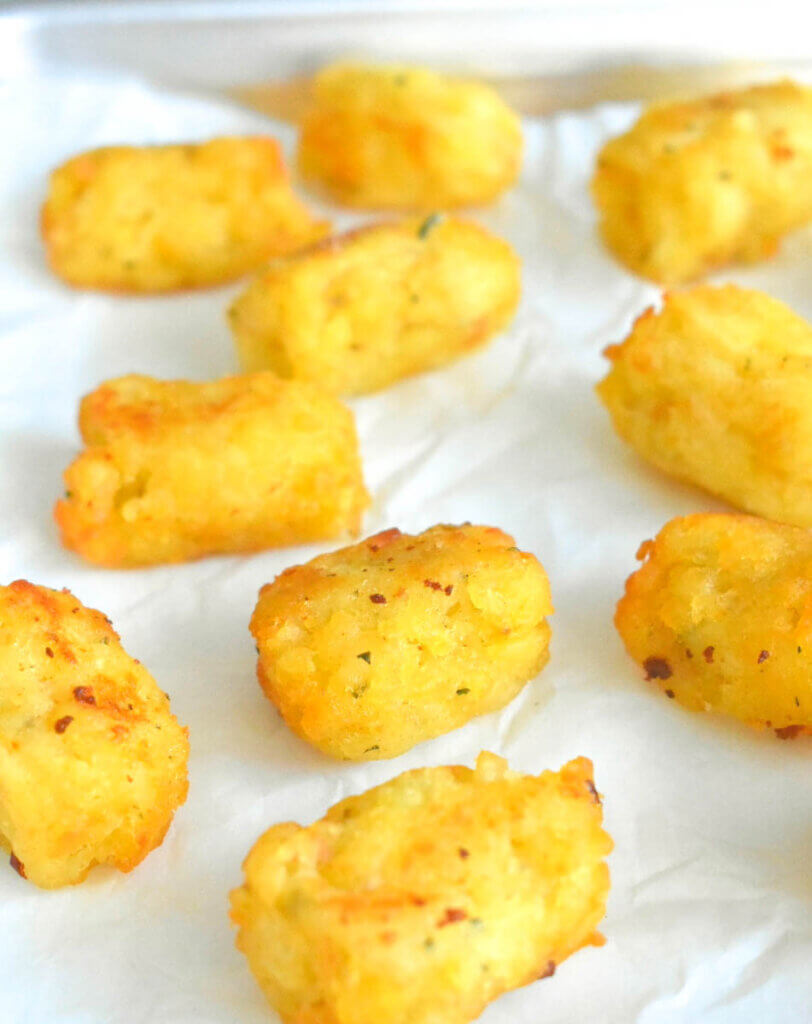 Tater tots on a baking panlined with parchment paper.