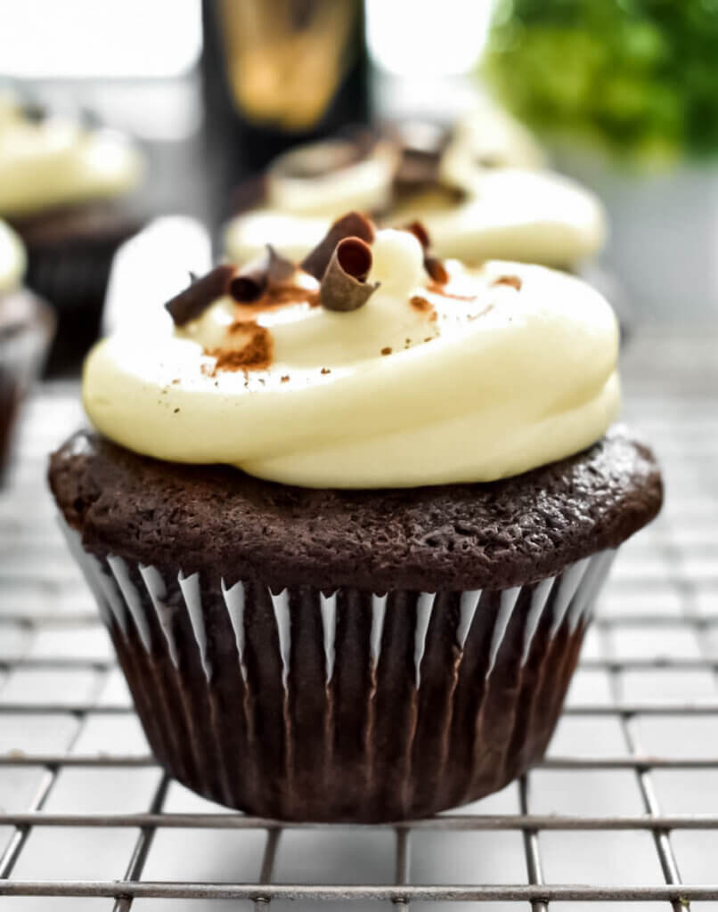 Closeup of a chocolate cupcake frosted with cream cheese frosting and with chocolate shavings on top.