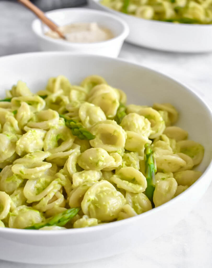 A plate of Orecchiette Pasta with Asparagus Pesto and a small bowl of parmesan.