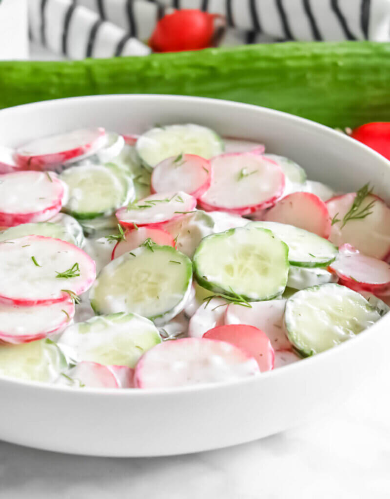 Closeup sideview of a Radish Cucumber Salad covered in a creamy dill dressing.
