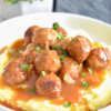 Salisbury steak meatballs served on top of mashed potatoes with lots of gravy.
