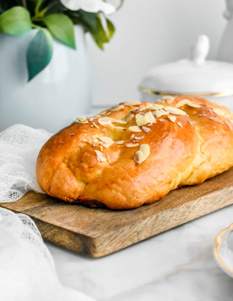 Baked Greek Easter Bread on a wooden cutting board set on a grey marble countertop.