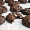 A bited Double Chocolate Chip Cookie on parchment paper with other cookies.
