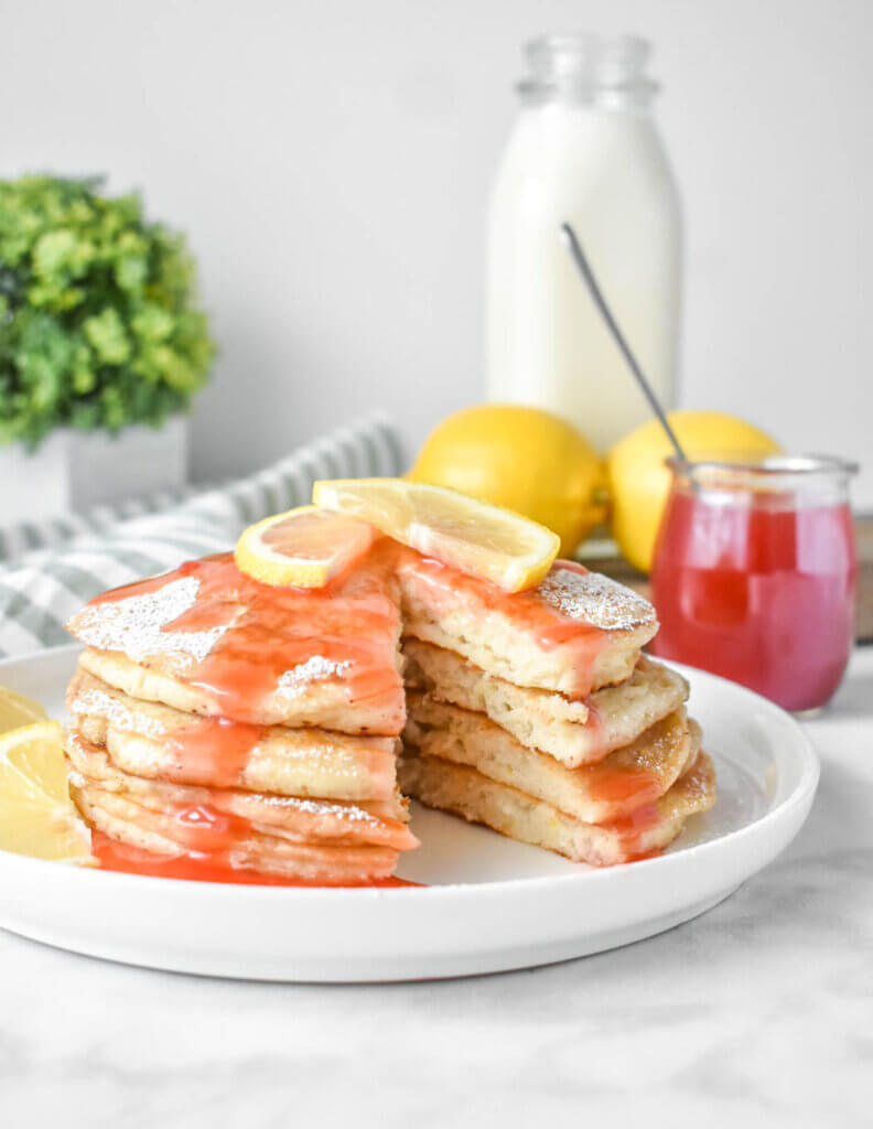 Sliced stack of Lemon Ricotta Pancakes with Strawberry Syrup