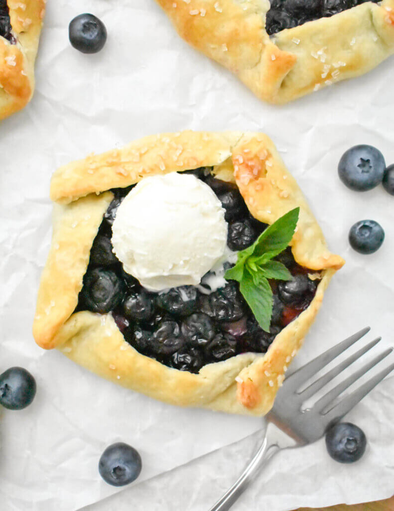 A Mini Blueberry Galette topped with a scoop of vanilla ice cream.