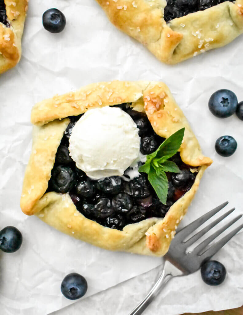 A mini blueberry galette topped with vanilla ice cream.