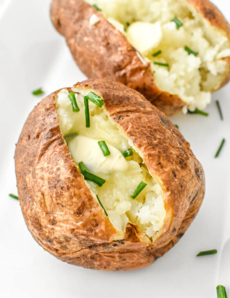 Air Fryer Baked Potatoes topped with butter and chives