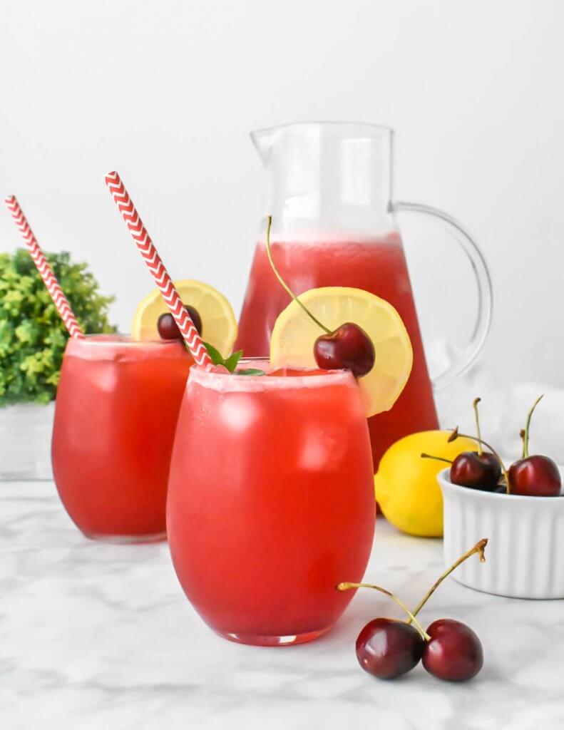 Cherry Lemonade glasses and pitcher with fresh cherry garnishes