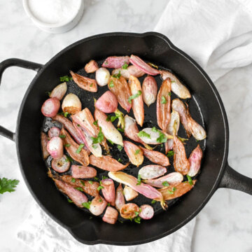 Cast Iron skillet with Roasted Radishes set on a table.