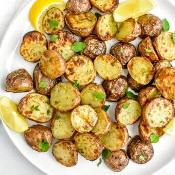 crispy air fryer Greek potatoes on a platter with lemon wedges
