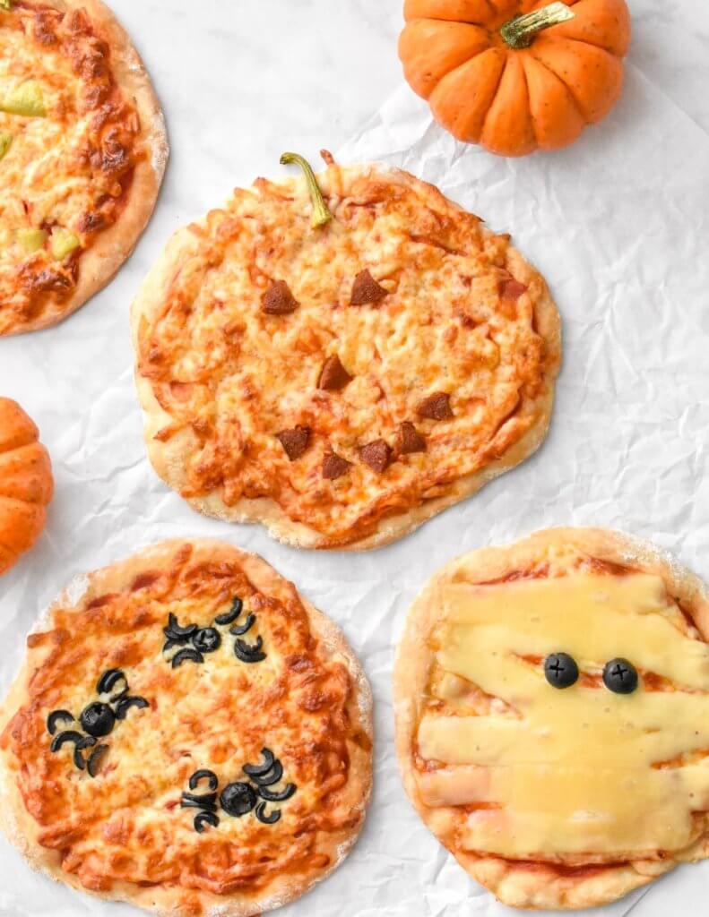 Halloween Pizzas with toppings arranged into spiders, a mummy and a jack o' lantern