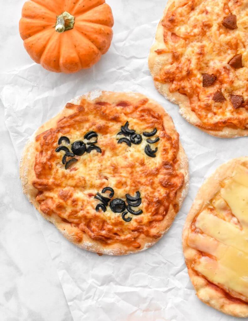 Spooky Halloween pizzas with spiders made out of black olives