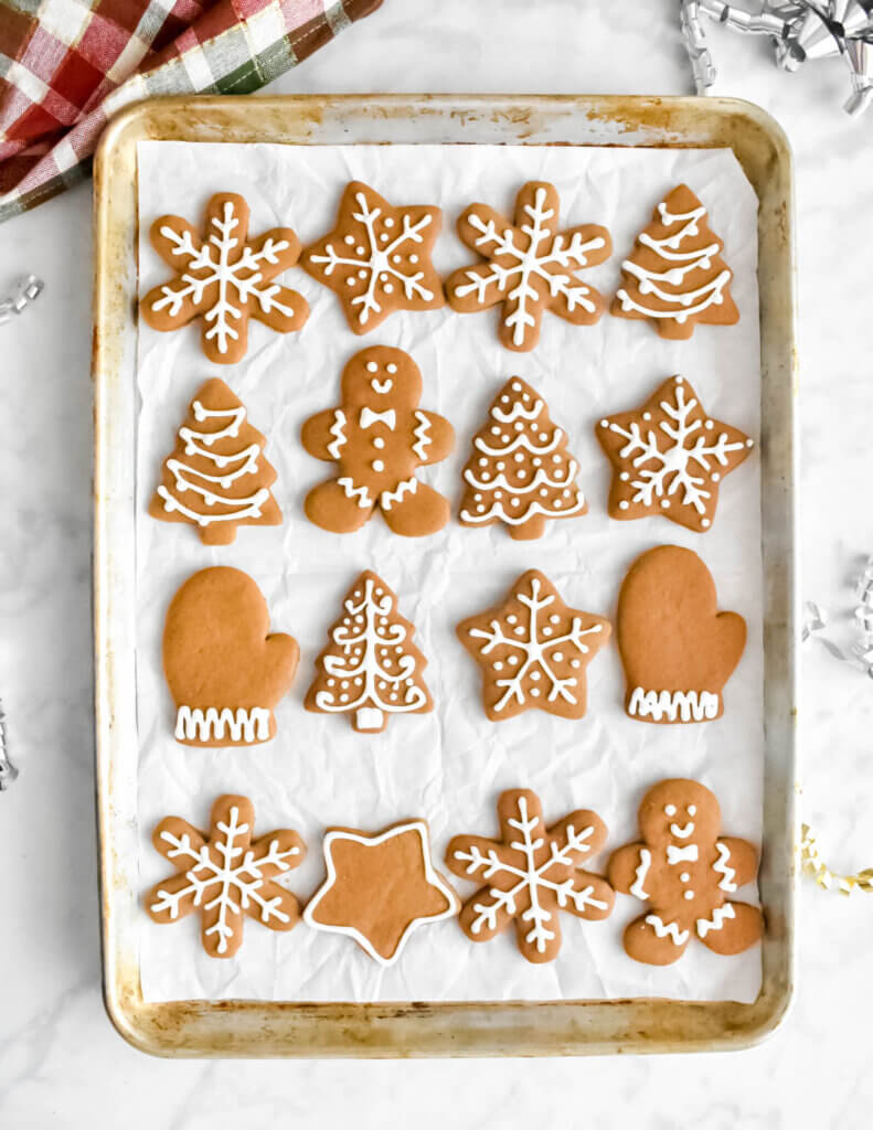 Tray of gingerbread cookie cutouts in the shape of stars, snowflakes, trees, men and mittens