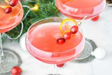 Holiday cocktails garnished with fresh cranberries and orange twirls