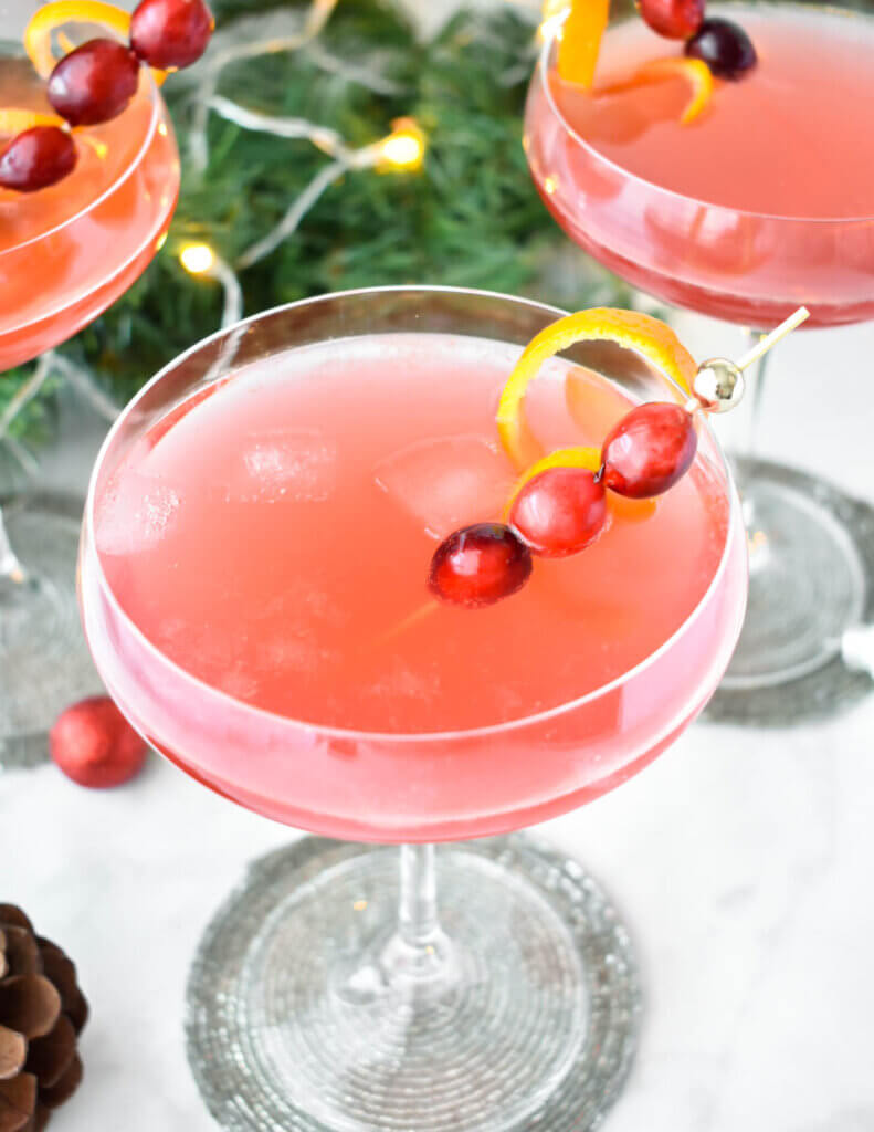 Close up top view of a pink holiday cocktail garnished with cranberries