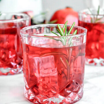 Pomegranate Rosemary Gin Fizz Cocktail glass garnished with a rosemary sprig