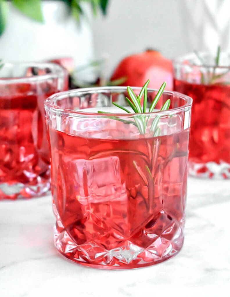 Pomegranate Rosemary Gin Fizz Cocktail glass garnished with a rosemary sprig