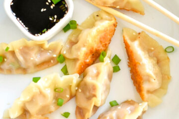 Pork Pot Stickers on a plate with soy sauce and chopsticks.