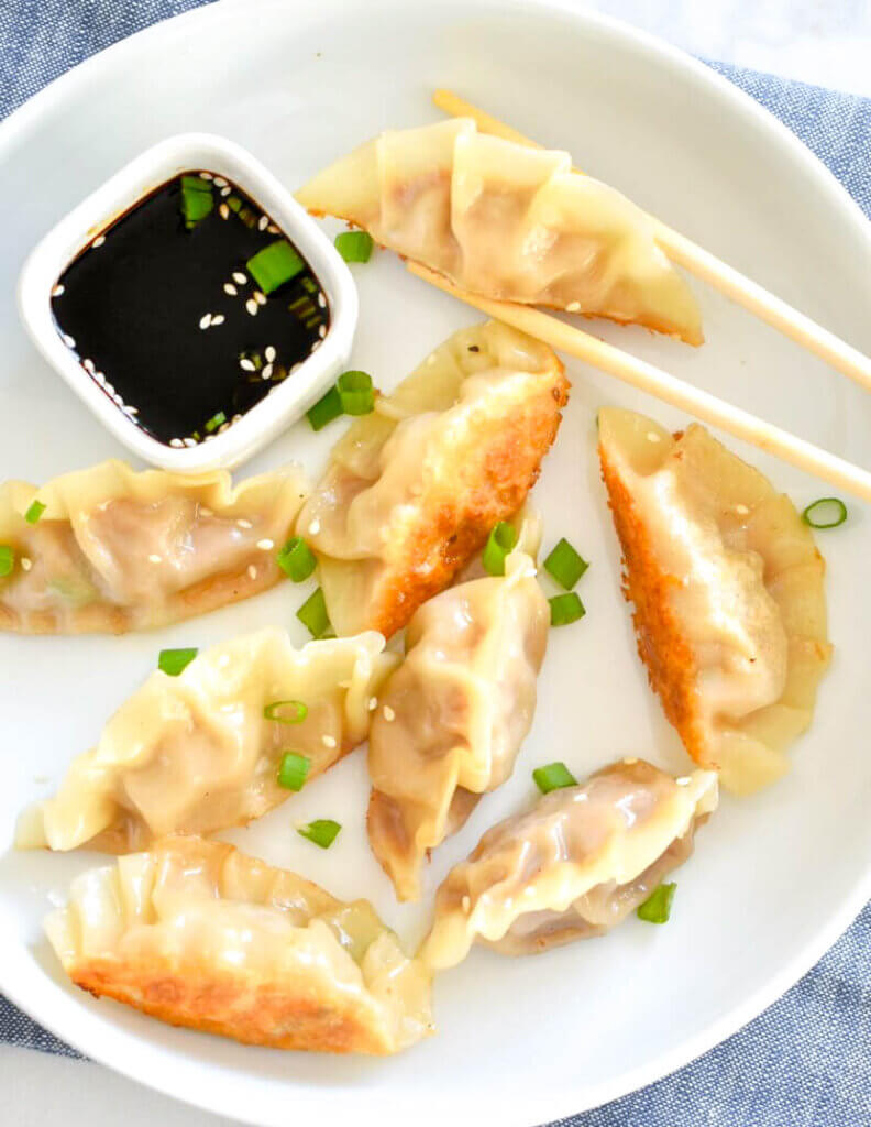 Pork Pot Stickers on a plate with soy sauce and chopsticks.