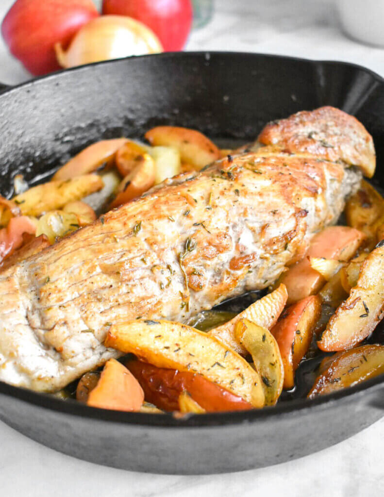 Cast iron skillet with cooked pork tenderloin and carmelized apples and onions.