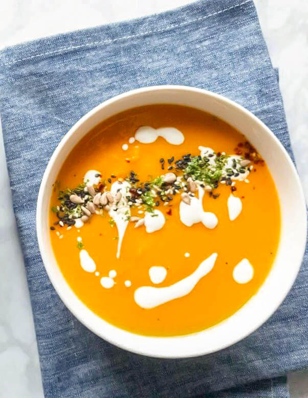 Bowl of Roasted Parsnip and Carrot Soup topped with seeds and herbs
