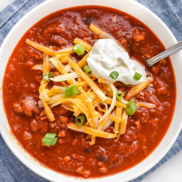 Bowl of Turkey Chili made in a slow cooker topped with cheese and sour cream