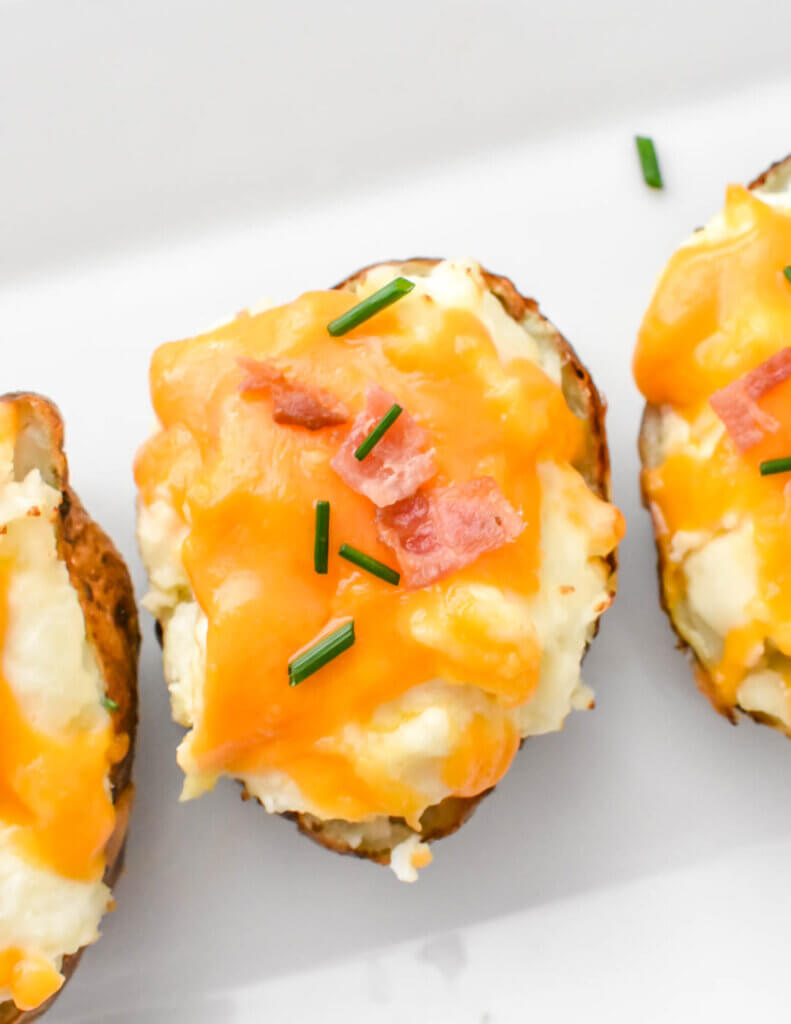 Topview of a twice baked potato topped with melty cheese, bacon and chives.